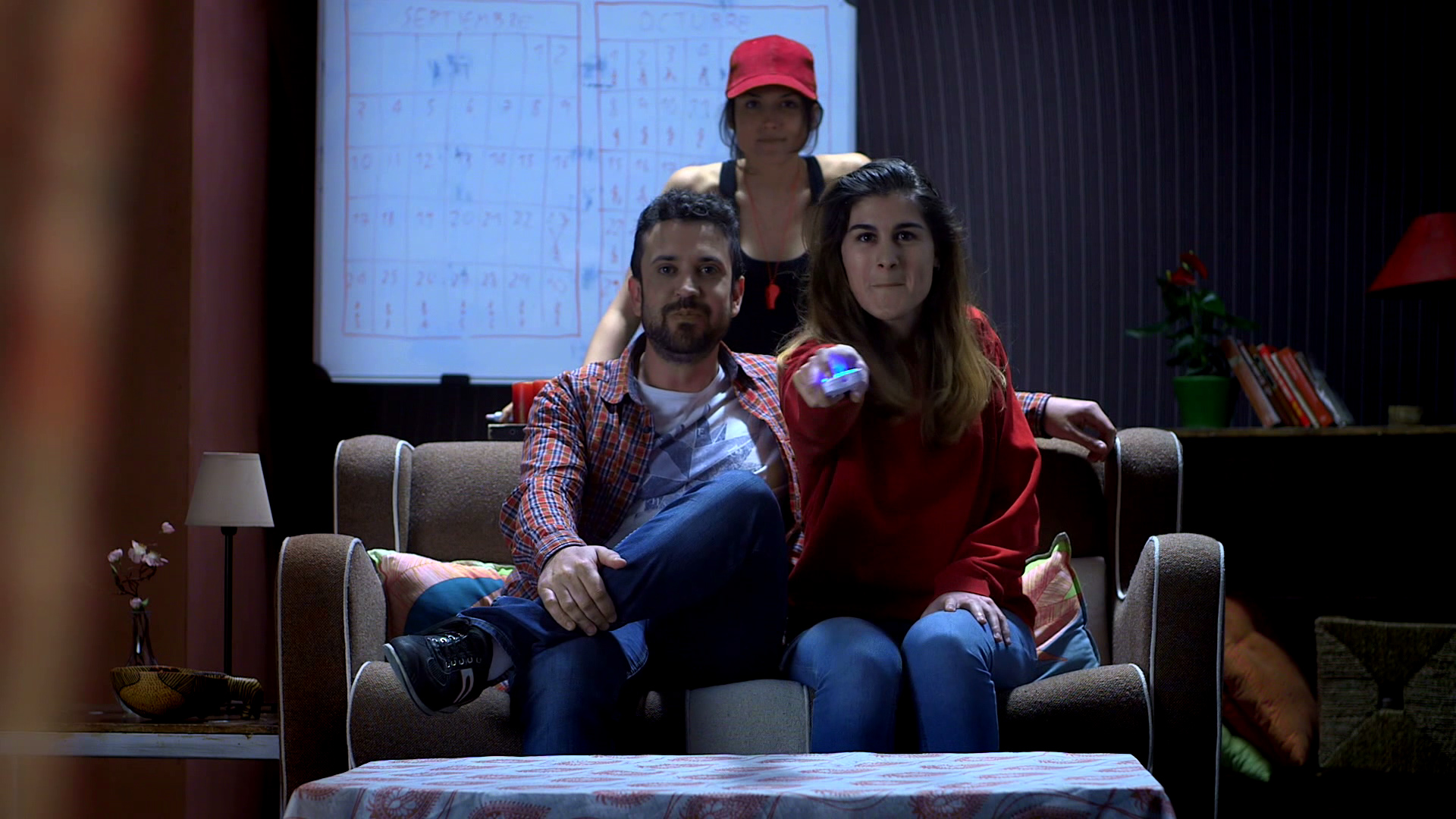 tres personas en un sillón mirando a cámara y una de ellas apuntando con un mando